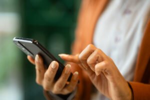 Manos de usuaria interactuando con la pantalla de un teléfono móvil para otorgar consentimiento y gestionar la privacidad de datos corporativos.